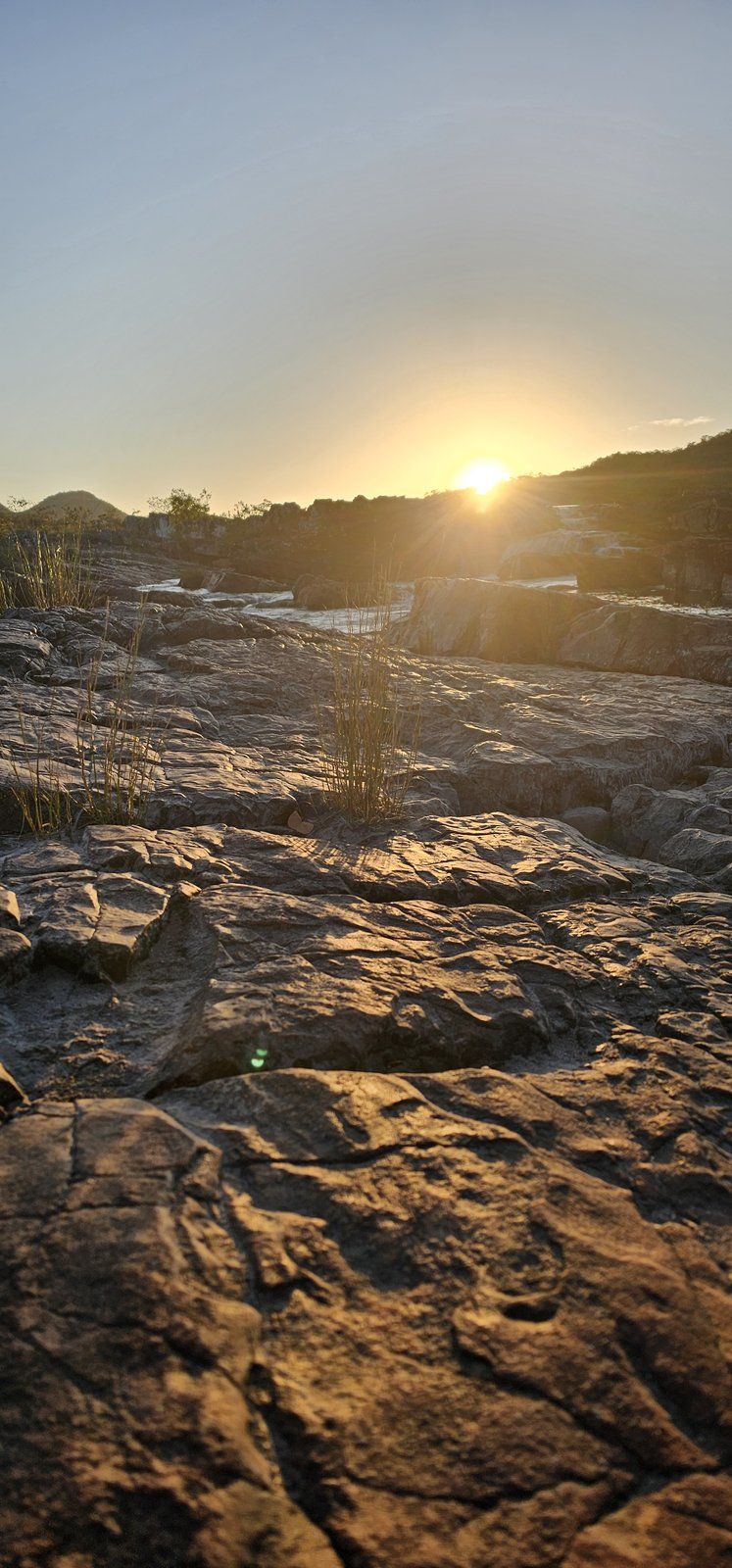 Amanhecer sobre lajedo e corredeira de rio