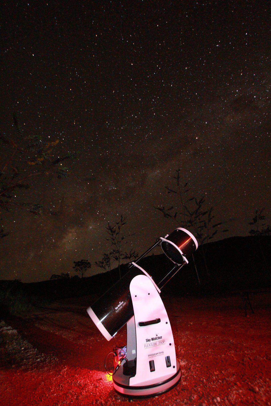 Telescópio Dobsoniano sozinho sob a Via Láctea, com a serra ao fundo